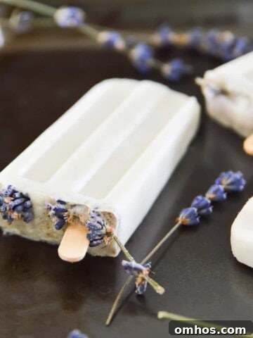 Lavender vanilla popsicles on a tray with lavender flowers around them.