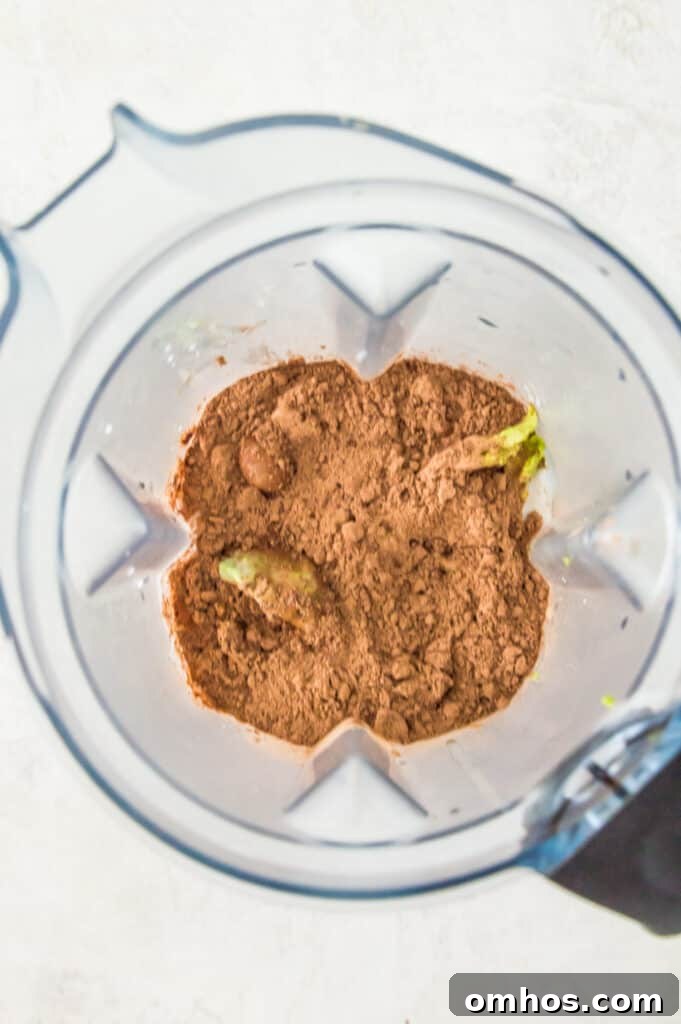 A blender filled with avocado flesh and cocoa powder.