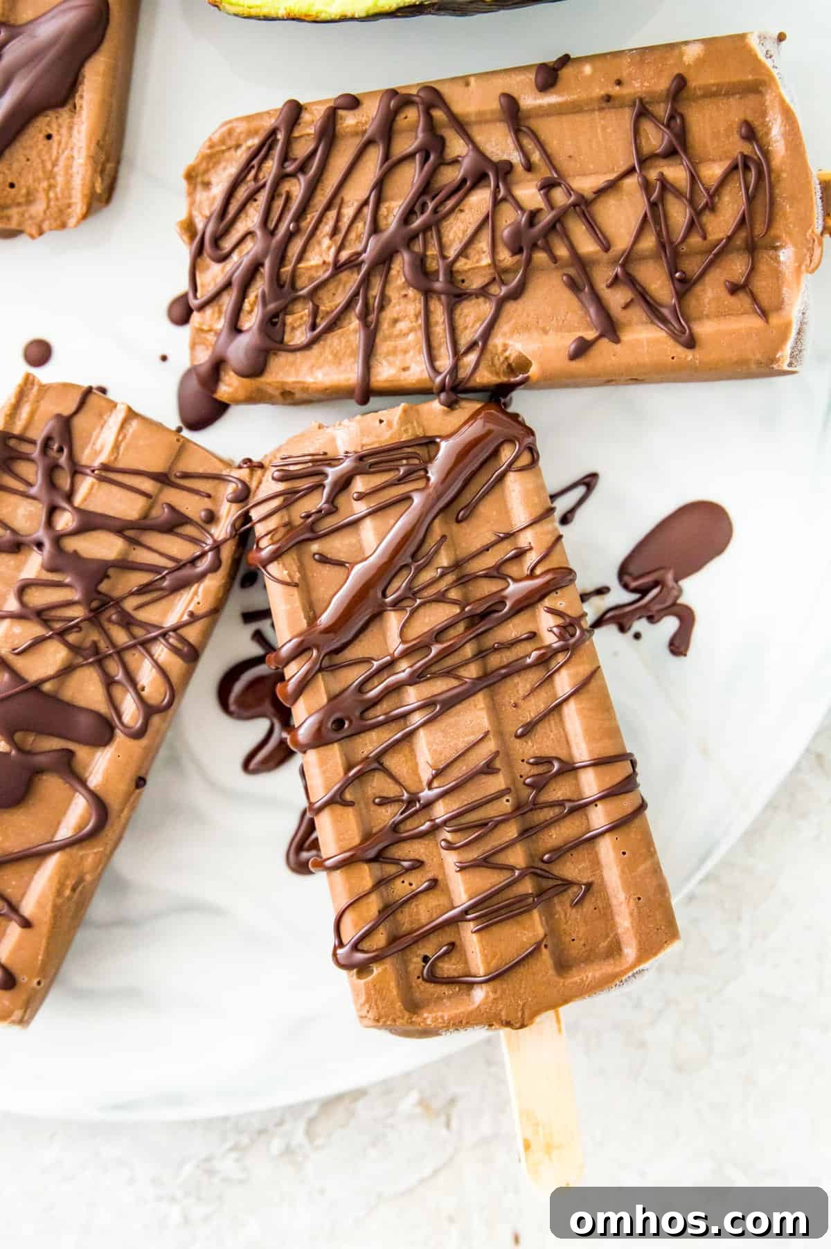 Avocado fudgesicles drizzled in melted chocolate on a serving tray.