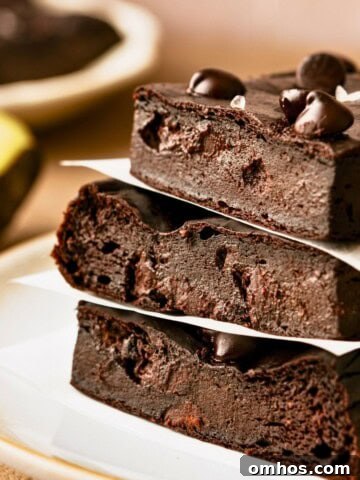 A stack of three avocado brownies topped with chocolate chips on a plate.