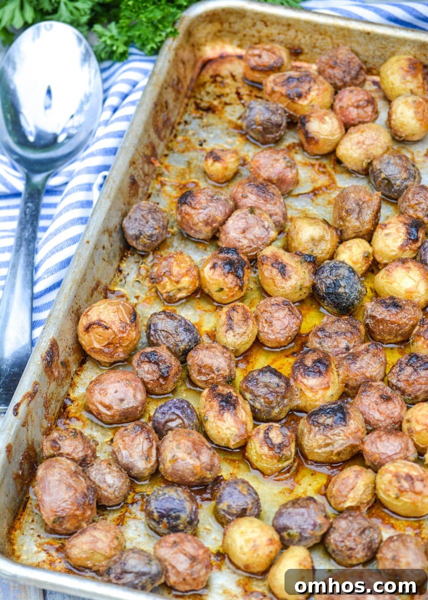 Crispy Roasted Potatoes with Mayonnaise 3 mayonnaise roasted potatoes on a rimmed baking sheet with a slotted silver serving spoon on the side