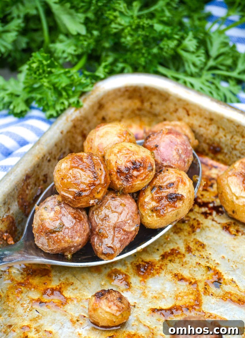 Crispy Roasted Potatoes with Mayonnaise 5 a slotted silver serving spoon full of mayonnaise roasted potatoes resting on a rimmed baking sheet