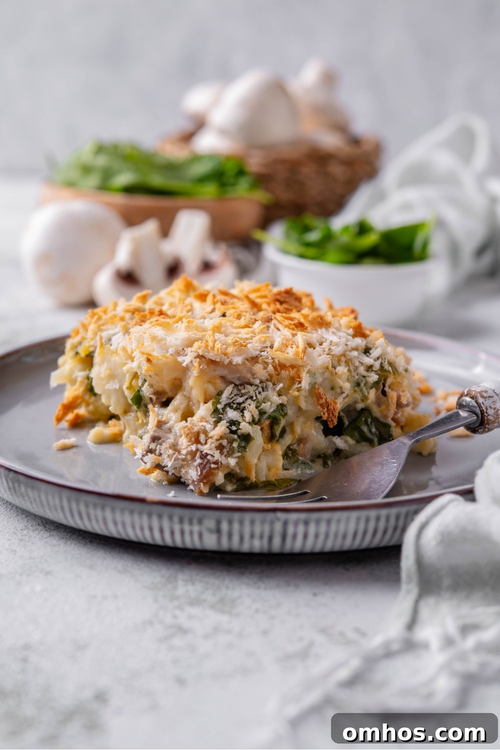A square serving of chicken cauliflower casserole on a plate with a fork on the plate next to it.