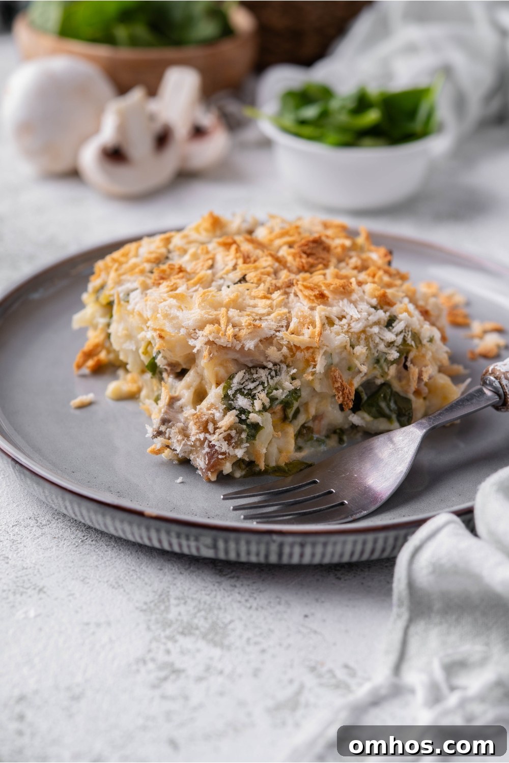 A square serving of chicken cauliflower casserole on a plate with a fork on the plate next to it.