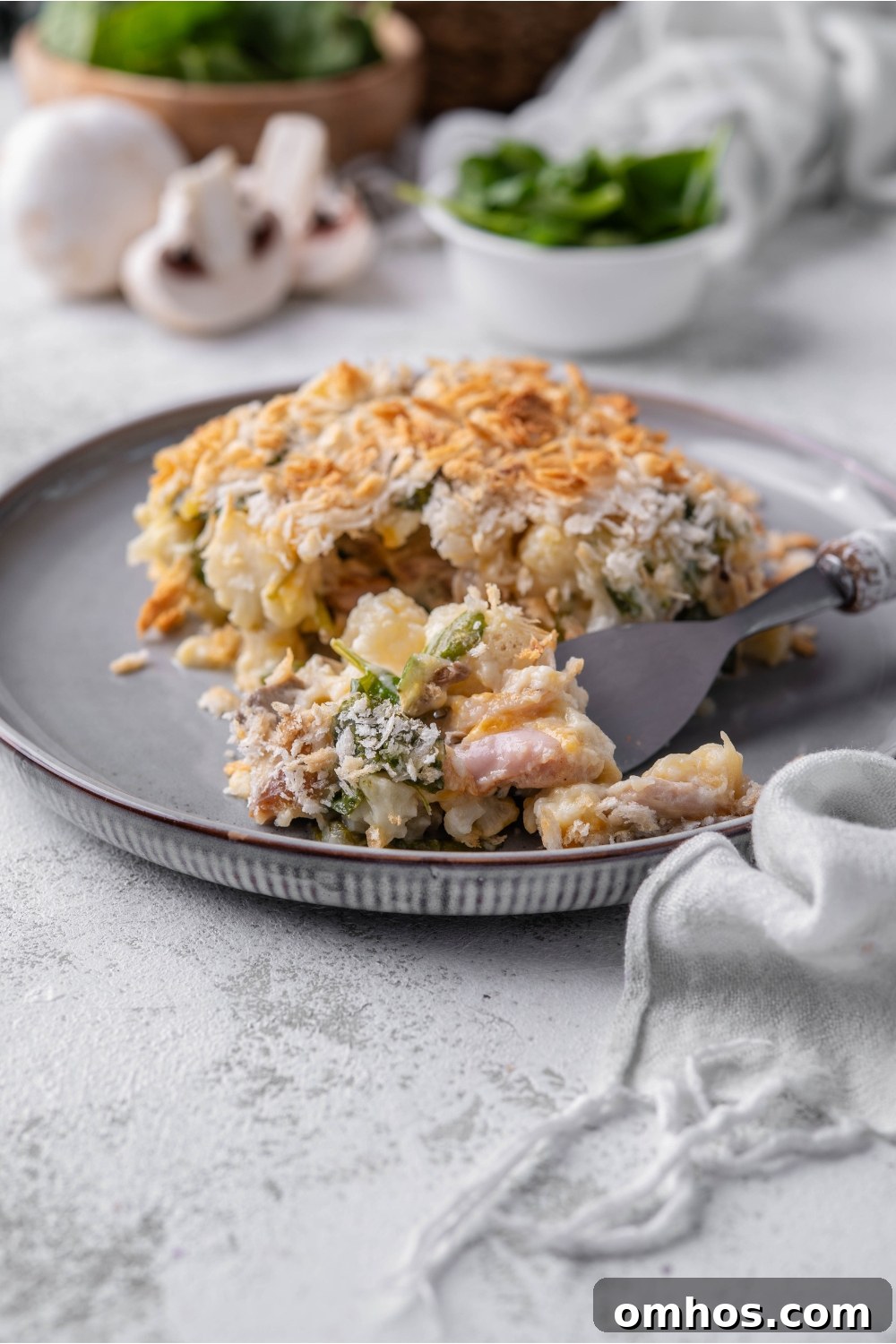 A square serving of chicken cauliflower casserole with a fork scooping a bite from the casserole.