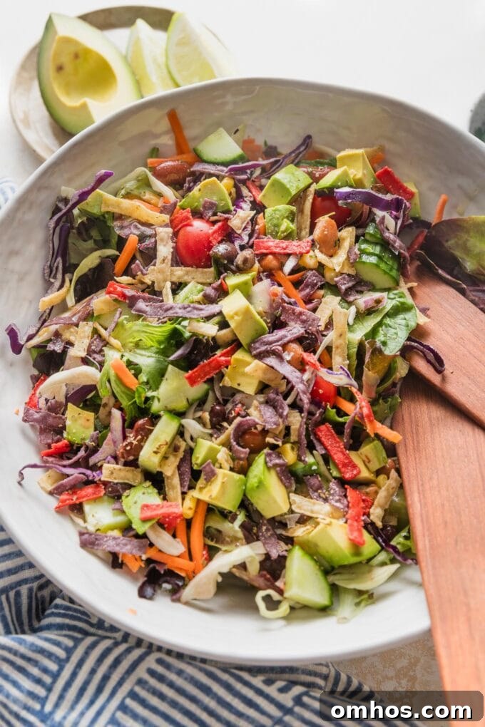 Crispy Baked Chicken and Black Bean Taquitos 4 Large white ceramic bowl full of an easy Mexican salad with avocado, cabbage, peppers, tortilla strips, and a red wine vinaigrette.