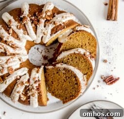 round plate with pumpkin bundt cake with cream cheese frosting and a couple slices cut off