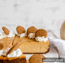 side of pumpkin cheesecake with gingersnap crust garnished with whipped cream and gingersnap cookie