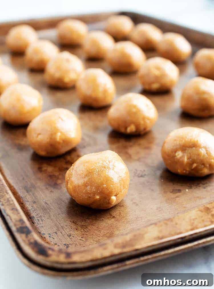 3 ingredient peanut butter balls lined up on a baking tray