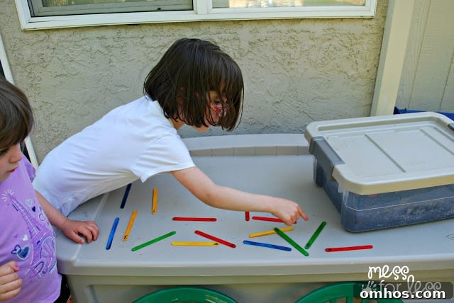 child counting popsicle sticks