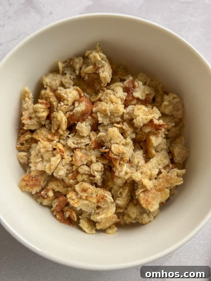 Scrambled oats cooked and sitting in a white bowl without toppings.