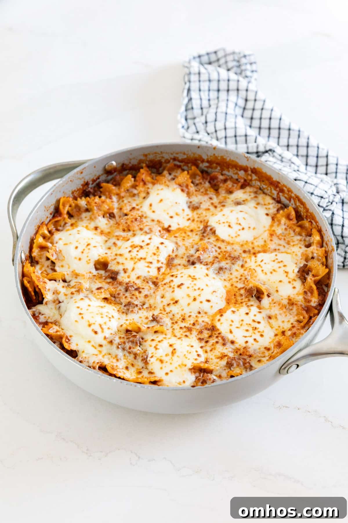 A pan of lasagna skillet with a striped towel behind it.