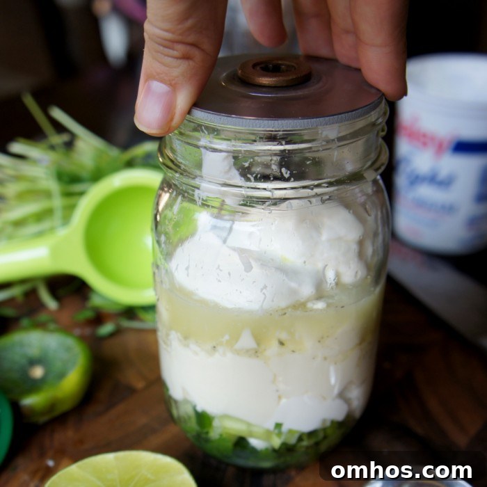 Salad dressing ingredients in a mason jar with blender blades on top