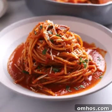 A grey bowl of spaghetti all'assassina with sauce over.
