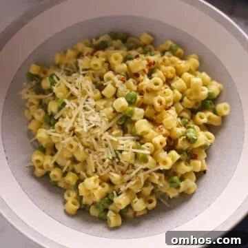A zoom in image of a grey plate with pasta and peas.