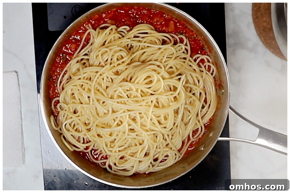 Pasta is added to the skillet with tomato sauce.