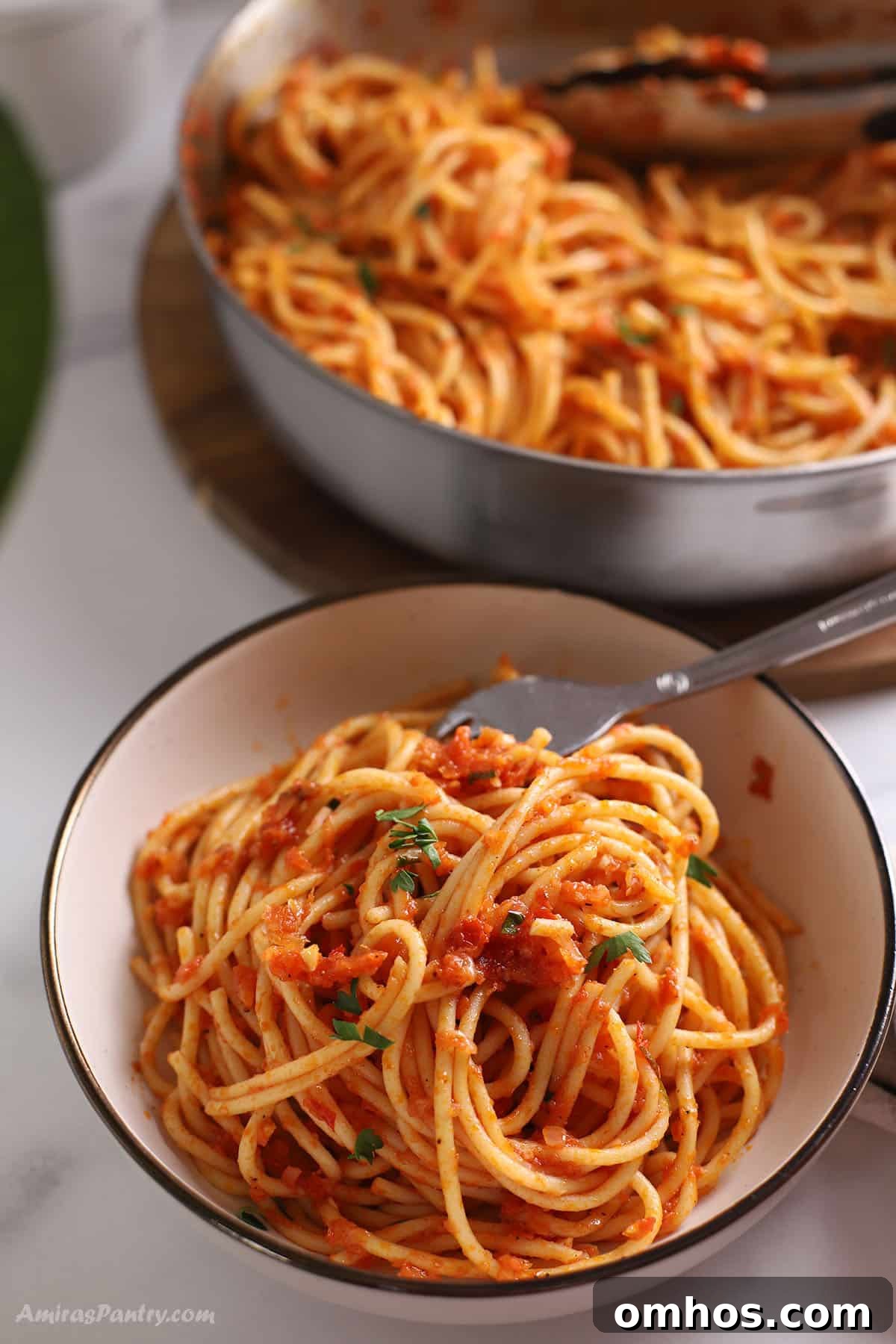 Harissa pasta in a small bowl with the whole skillet in the back.
