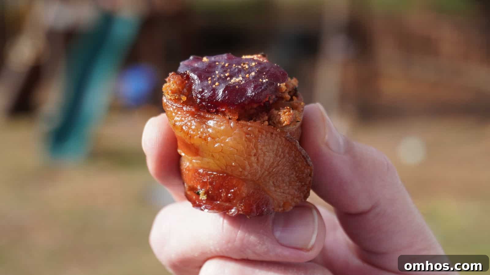 man holding a turkey shot, kielbasa wrapped in bacon, filled with stuffing, and topped with cranberry sauce