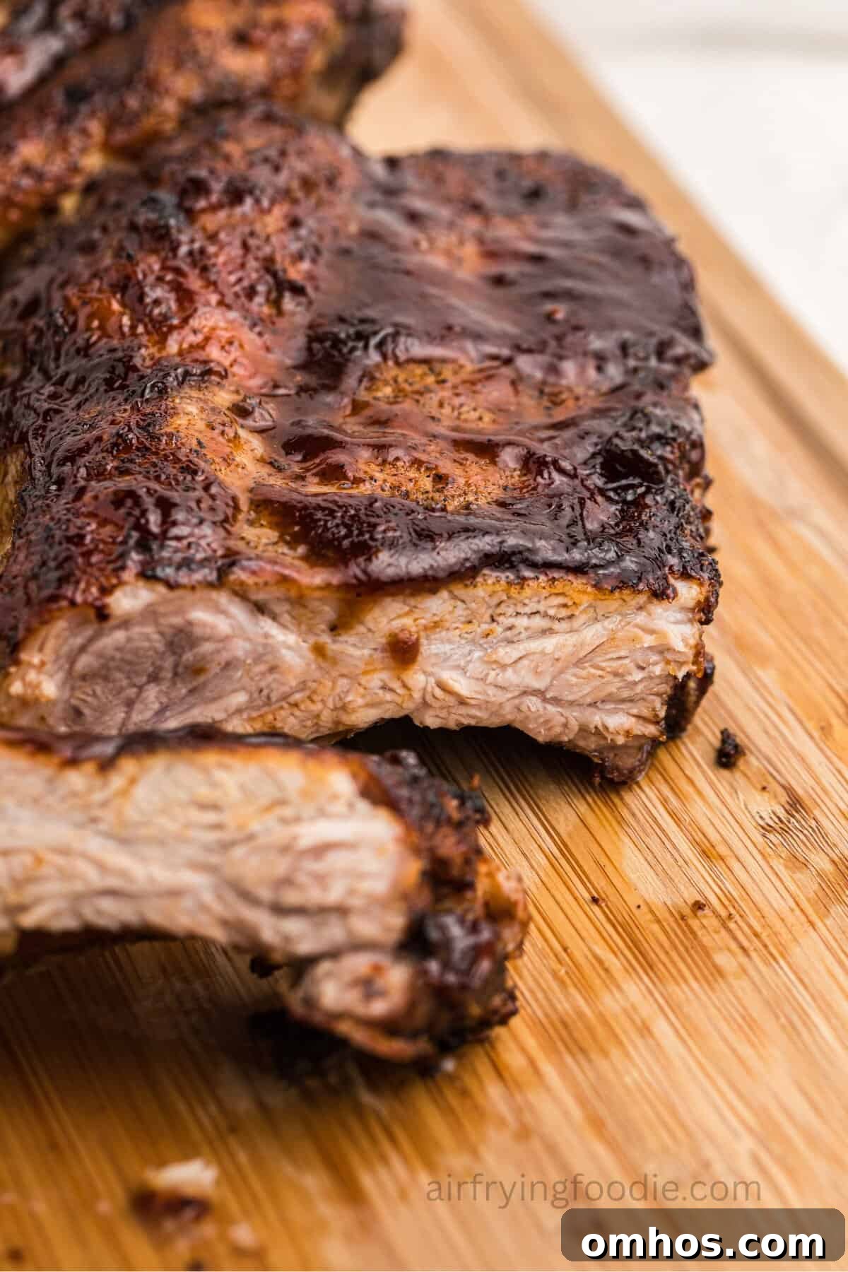 Crispy Air Fryer BBQ Ribs Recipe with Sticky Glaze 2 Air fryer ribs slathered in bbq sauce and sliced on a wooden cutting board.