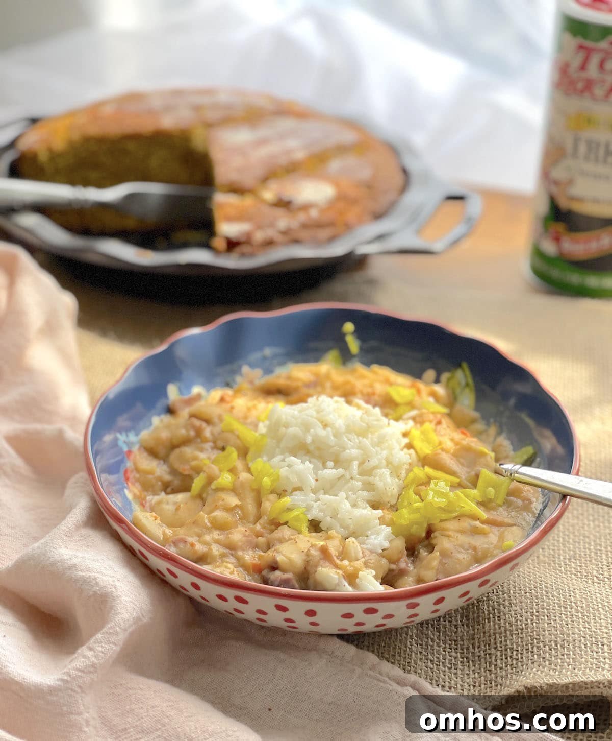 A bowl of Cajun seasoned butter beans with rice and pickled peppers in front of sweet potato cornbread.
