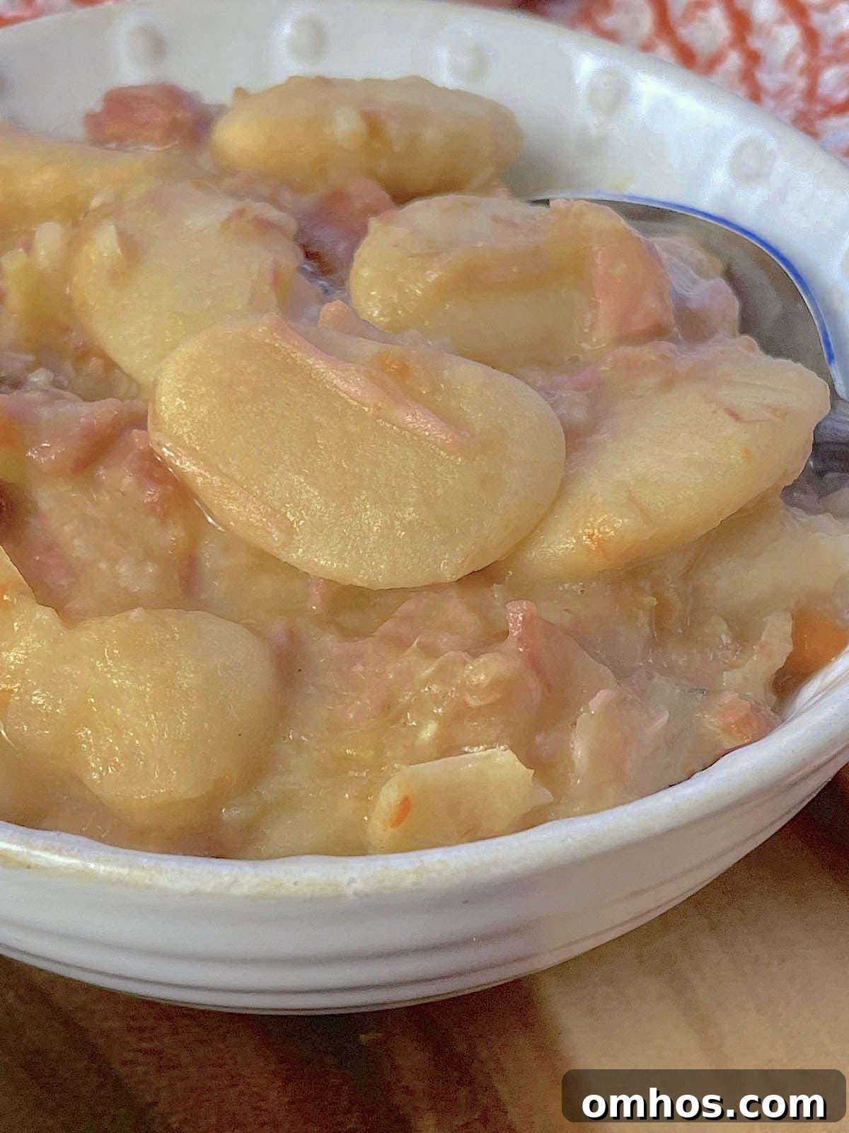 A small white bowl of Southern lima beans cooked with ham.