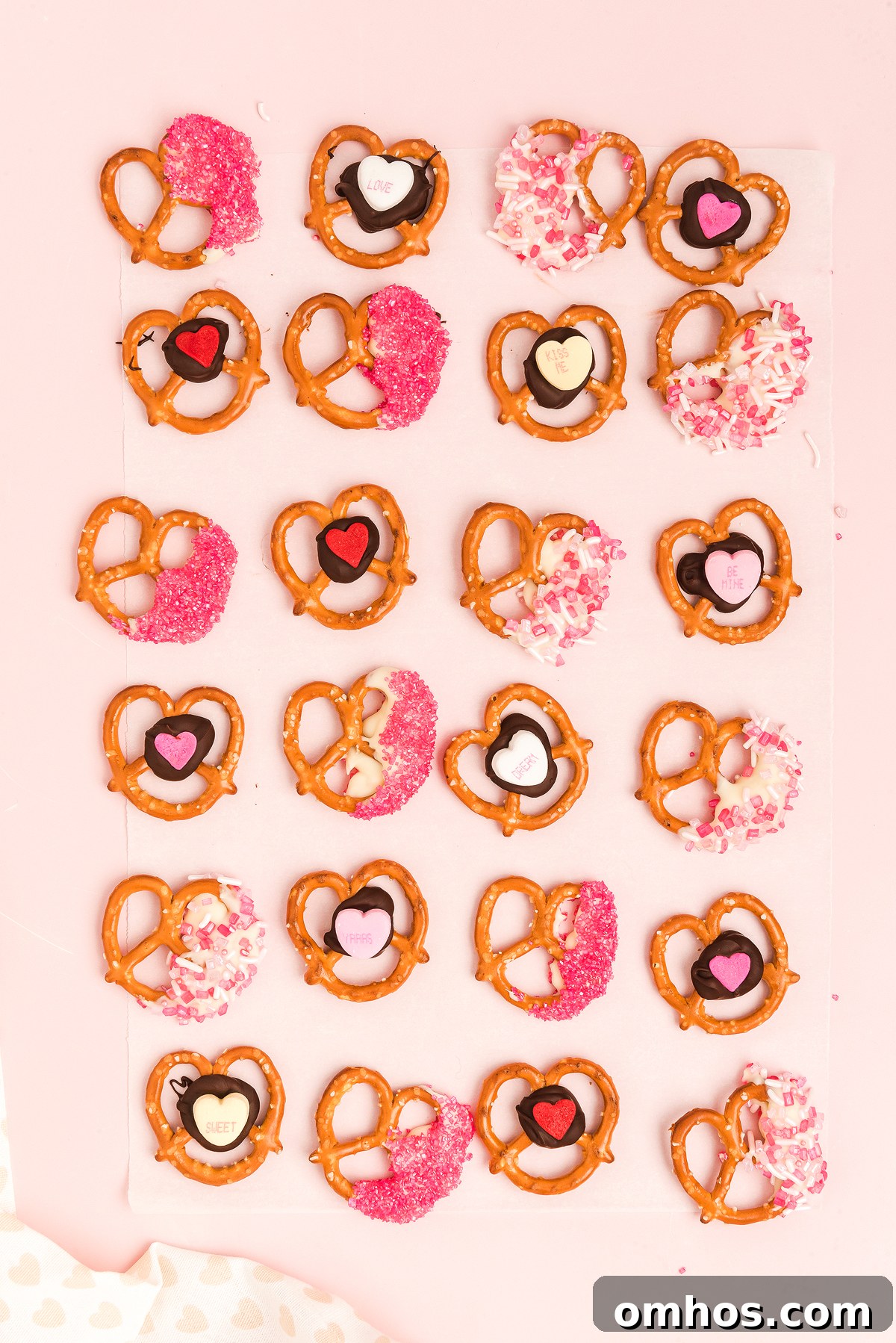 Valentine Pretzel Snack Bites Recipe 3 Heart-shaped Valentine pretzels decorated with pink, red, and white sprinkles and candy hearts make the perfect Valentine’s Day treat on parchment paper.