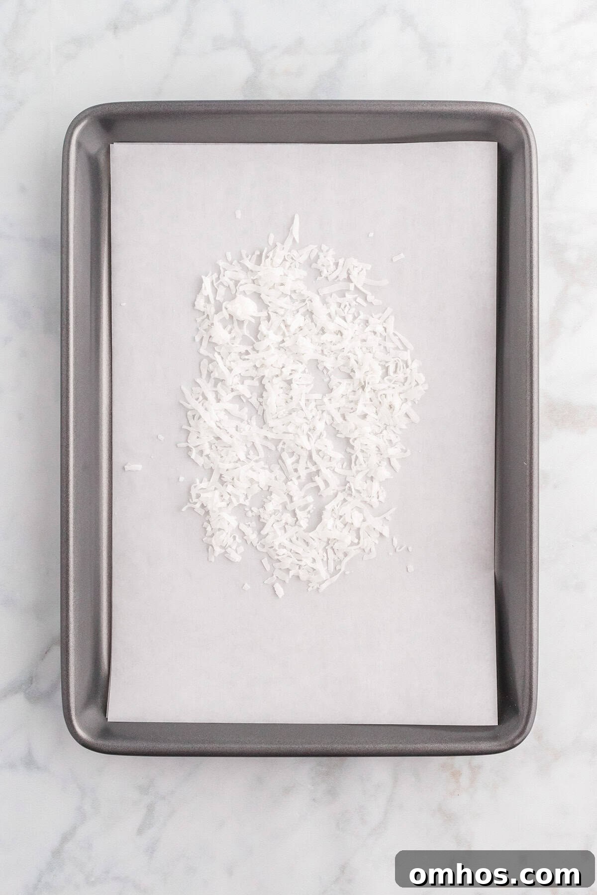 Shredded coconut on a baking sheet ready to toast for topping.