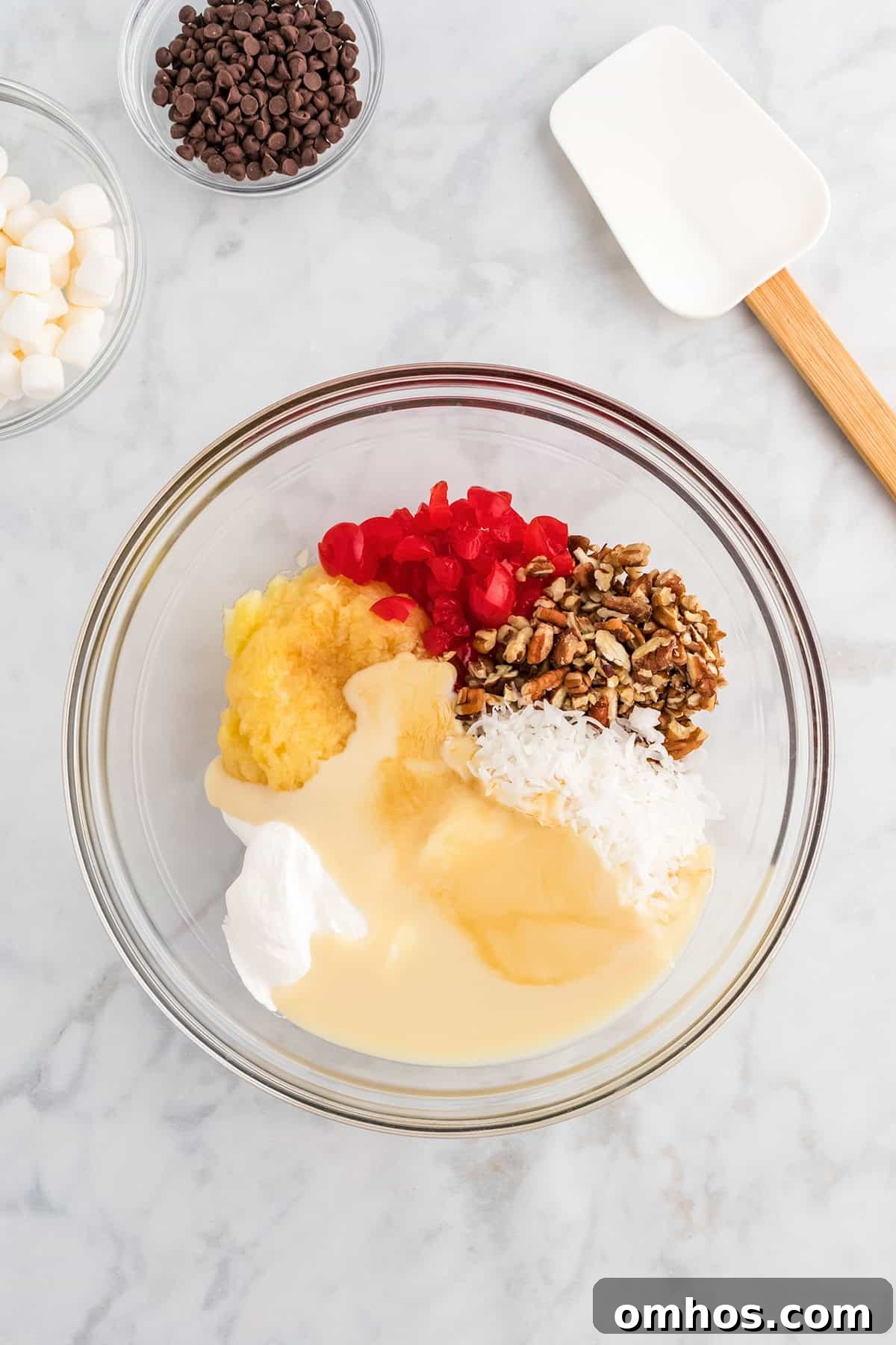 Bowl of crushed pineapple, cherries, pecans, coconut, and sweetened condensed milk ready to be mixed into pie filling.
