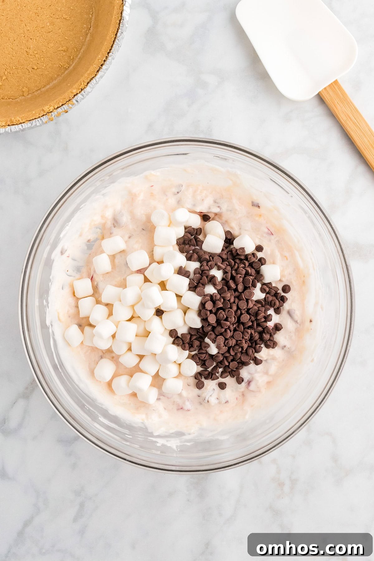 Creamy pie filling in a bowl with mini marshmallows and chocolate chips on top.