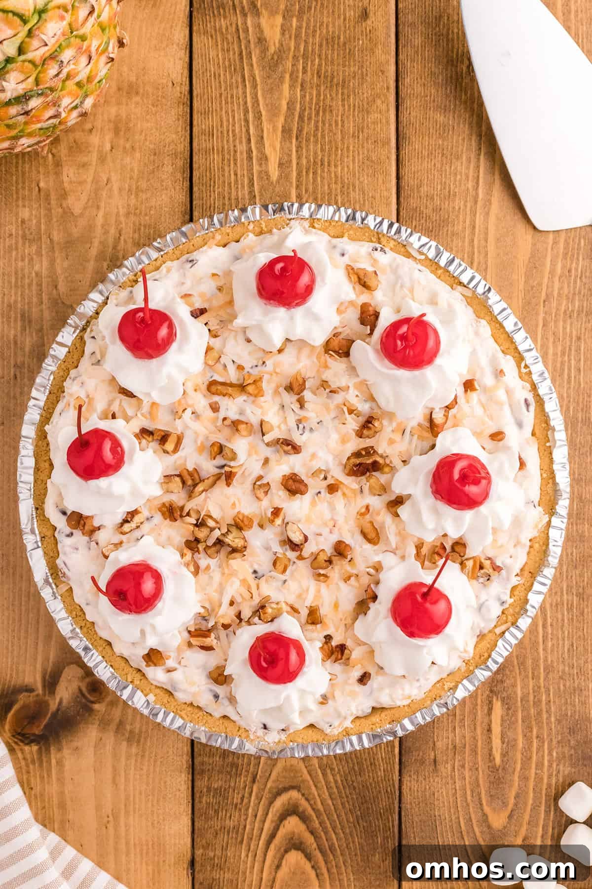 A slice of Million Dollar Pie topped with whipped cream, chopped nuts, toasted coconut, and a maraschino cherry.