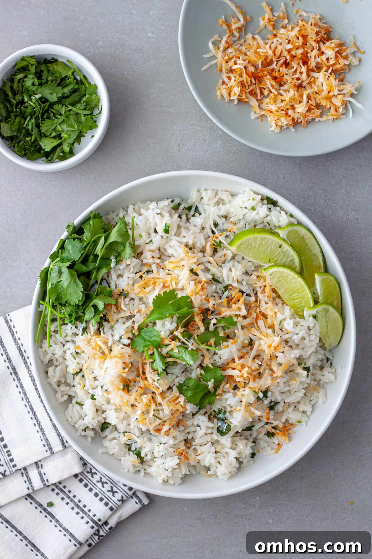 Fragrant Coconut Cilantro Rice Recipe 2 A white serving bowl with coconut cilantro rice topped with toasted coconut and cilantro leaves.