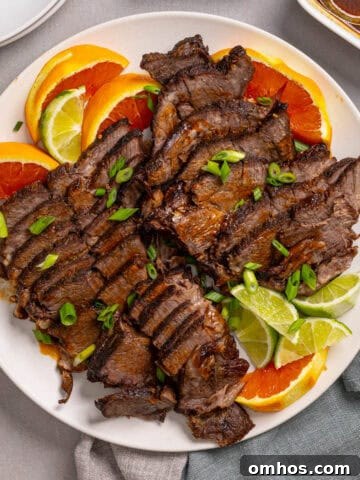 A close up of a platter with braised chuck roast sliced thin garnished with orange and lime.