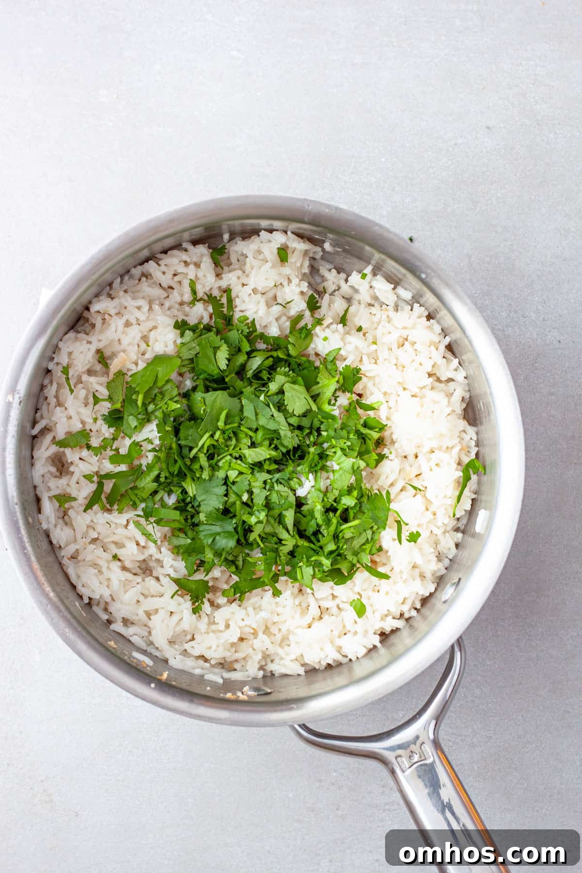 Fragrant Coconut Cilantro Rice Recipe 7 Chopped cilantro added to a saucepan with cooked coconut rice.