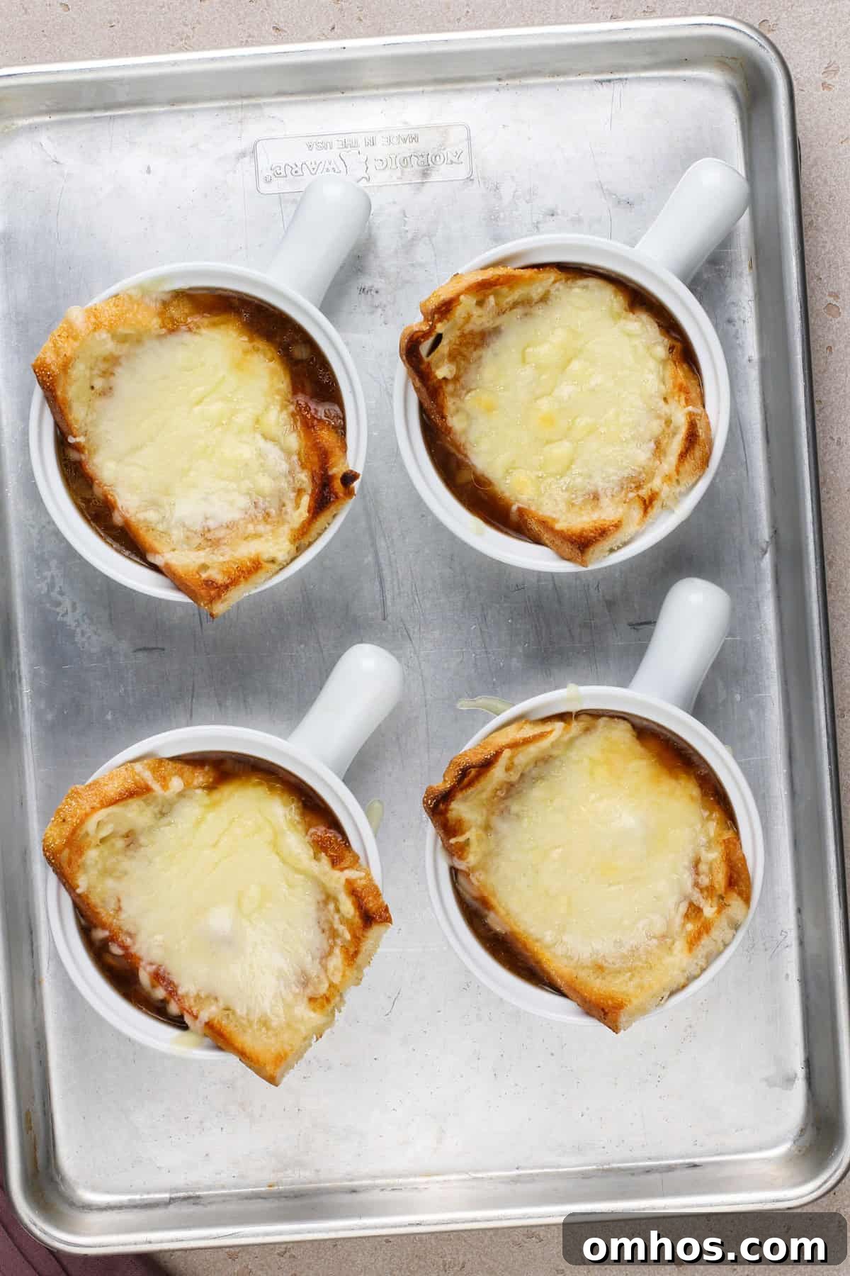 Four bowls of french onion soup freshly pulled from under the broiler.