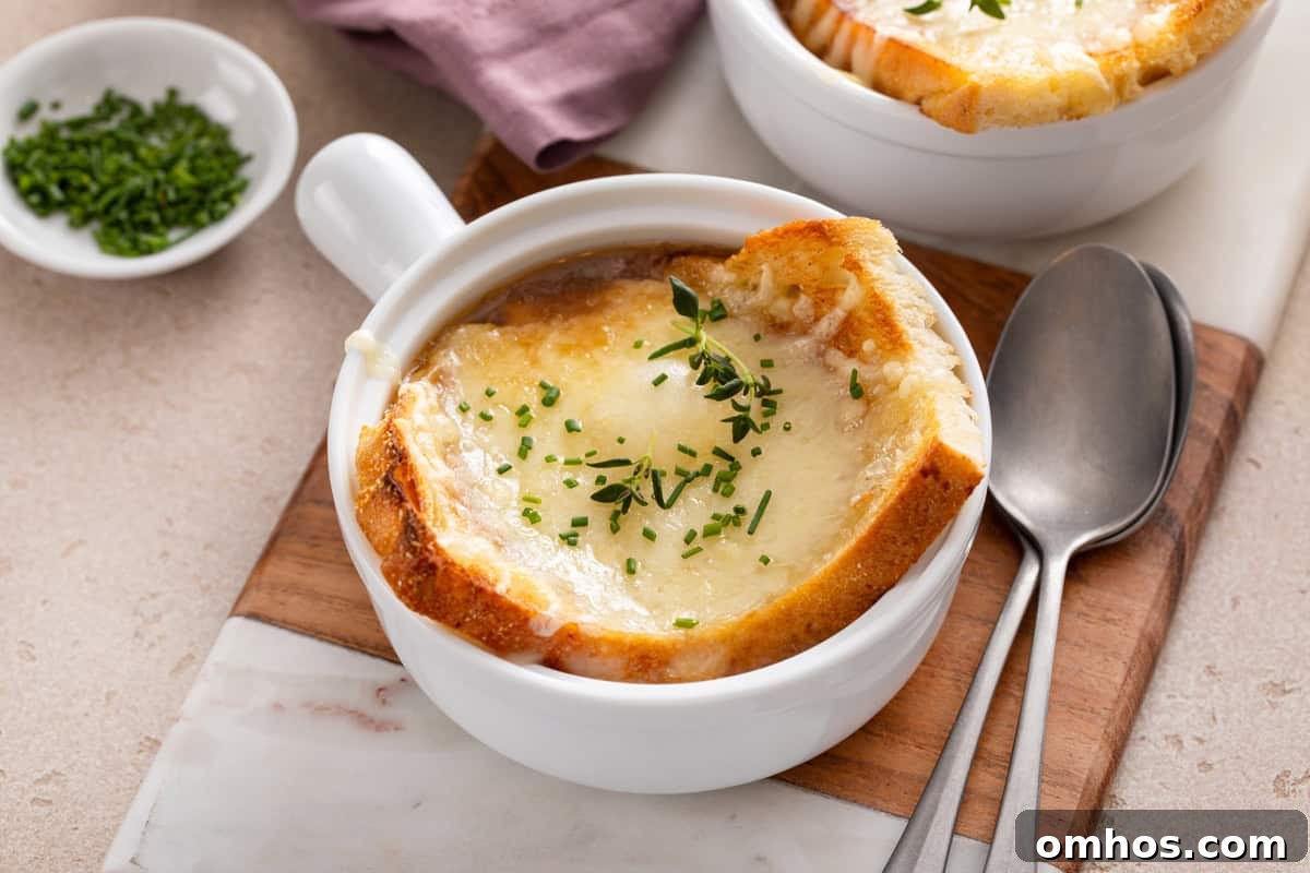 French onion soup topped with cheese toast in a white bowl.