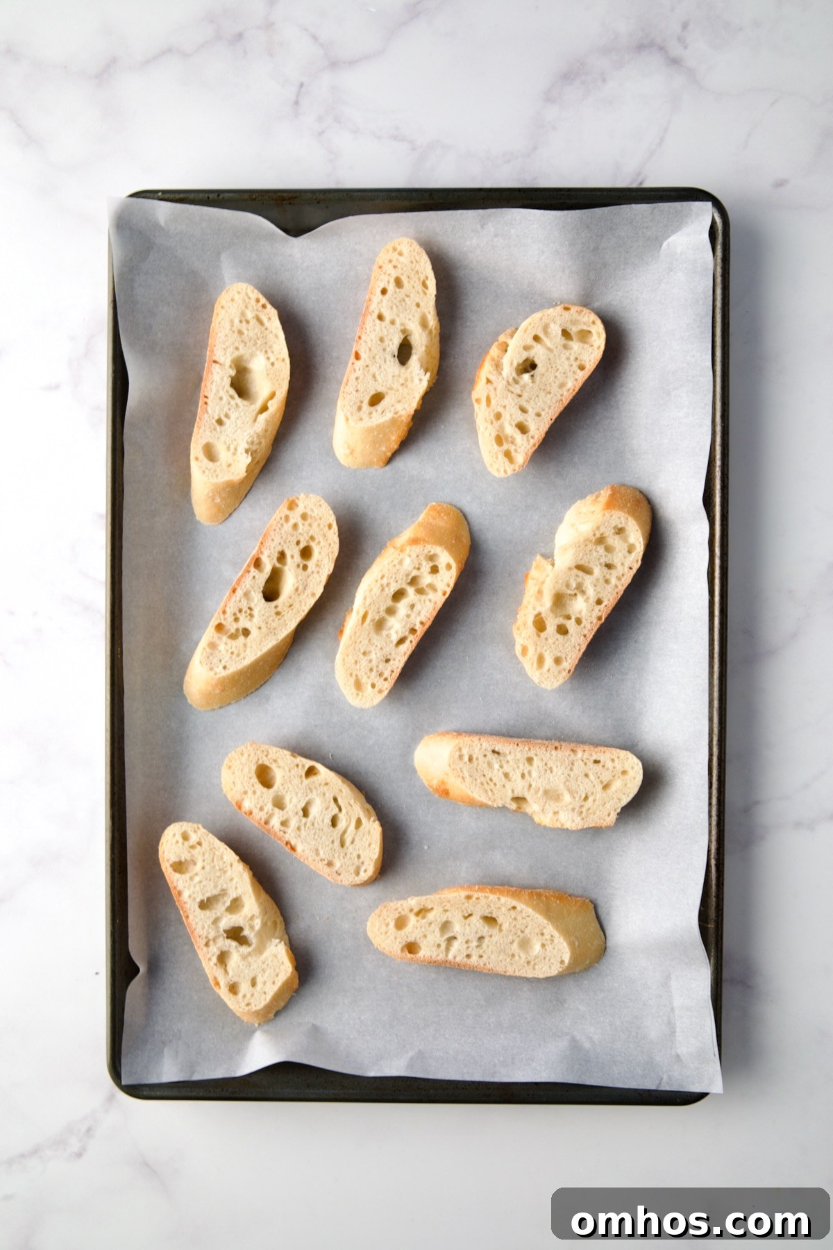 Bread slices on parchment paper lined rimmed baking sheet.