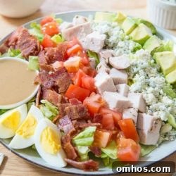 Classic Cobb Salad with Bacon, Avocado and Blue Cheese 8 Rows of Cobb Salad Ingredients on a Plate with Dressing Ramekin