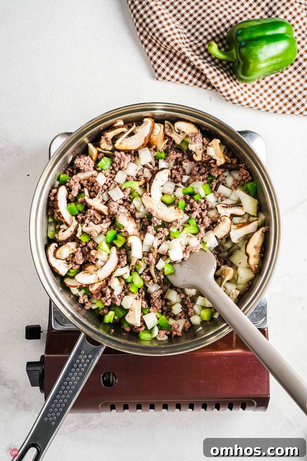 skillet with onions, peppers, and mushrooms in a skillet