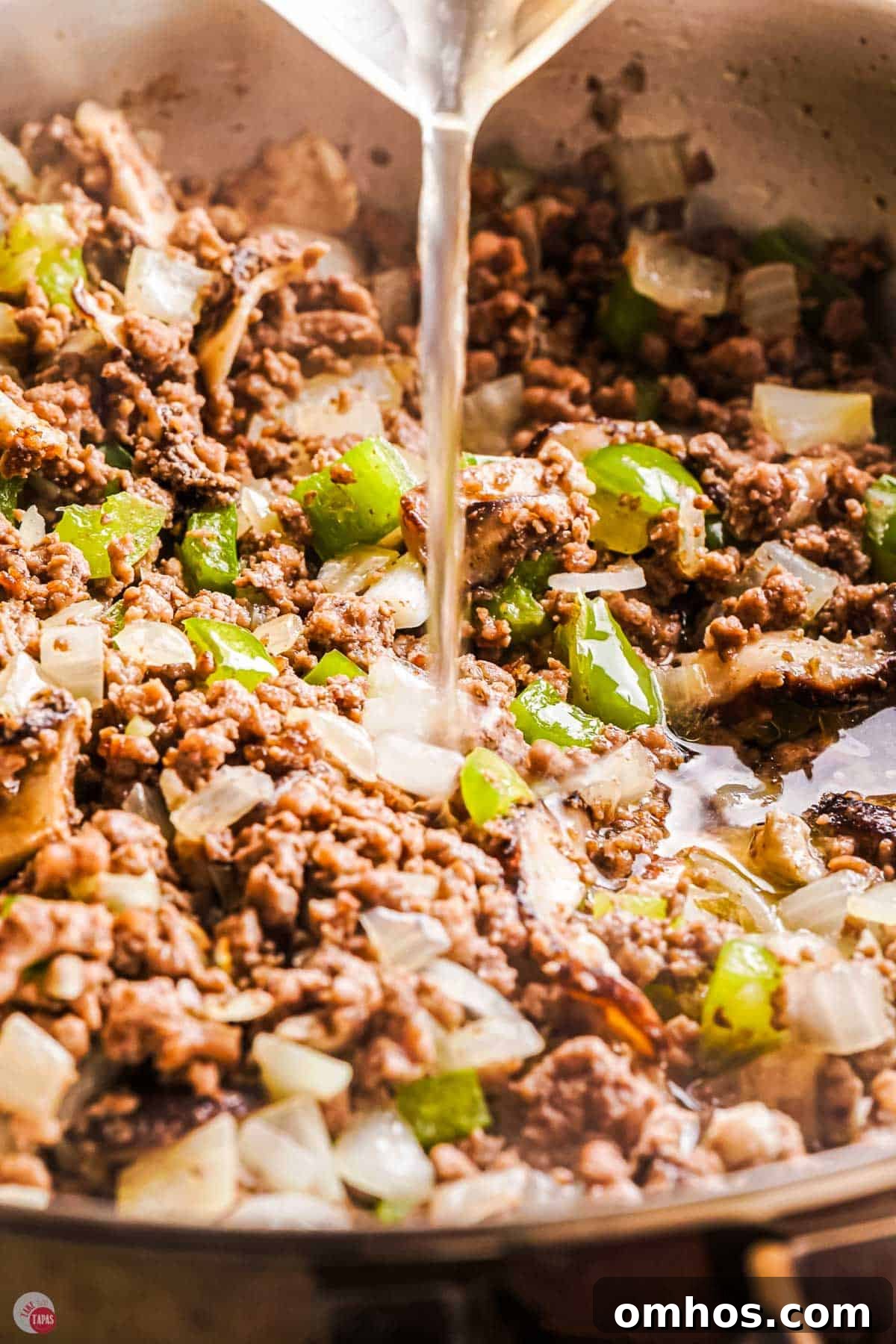 close up of ground beef with seasoning and broth cooking in a skillet