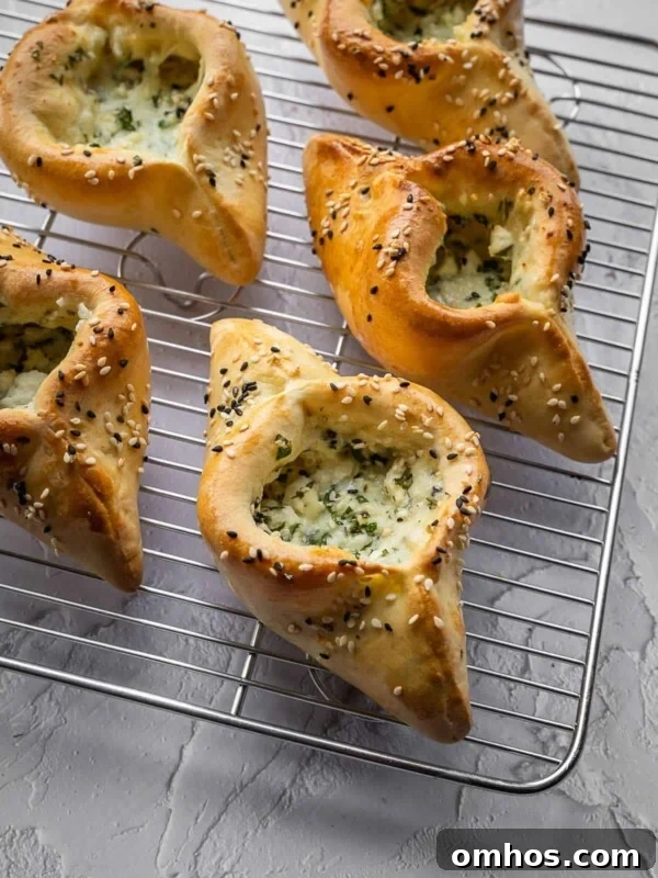 Cheese and herb fatayer pastries with sesame seeds on a cooling rack.