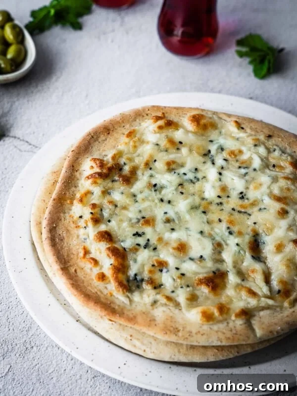 Cheesy flatbreads on a plate with olives and mint tea on the side.