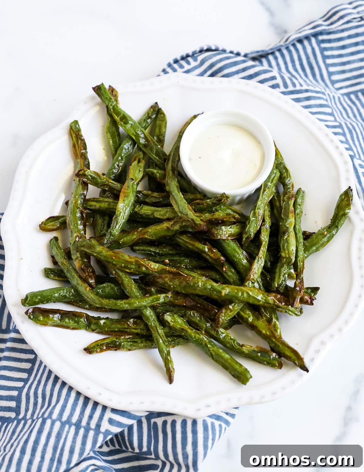An overhead picture of air fried green beans on a white plate