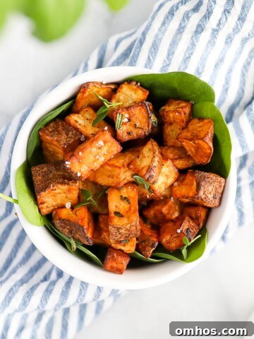 An overhead shot of crispy diced potatoes, garnished with salt and fresh herbs.