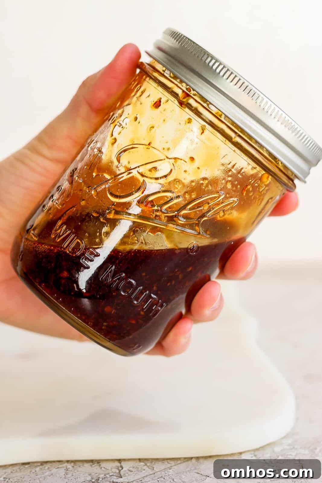 A hand holding a jar of fried rice sauce before adding it to Blackstone shrimp fried rice.