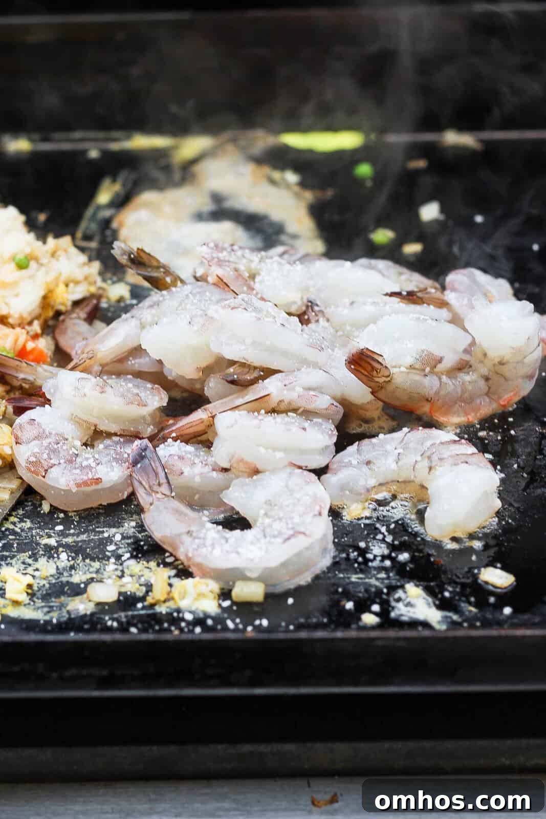 Large shrimp added to the hot cooktop for Blackstone shrimp fried rice.