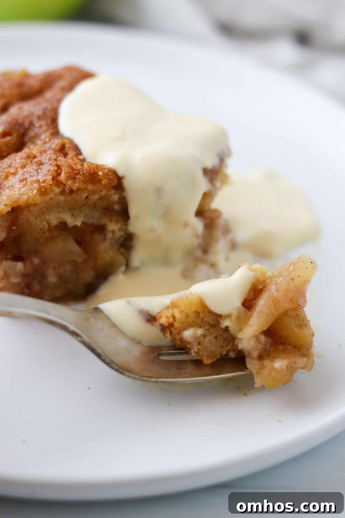 Close up of Swedish Apple Pie on a fork topped with vanilla sauce.