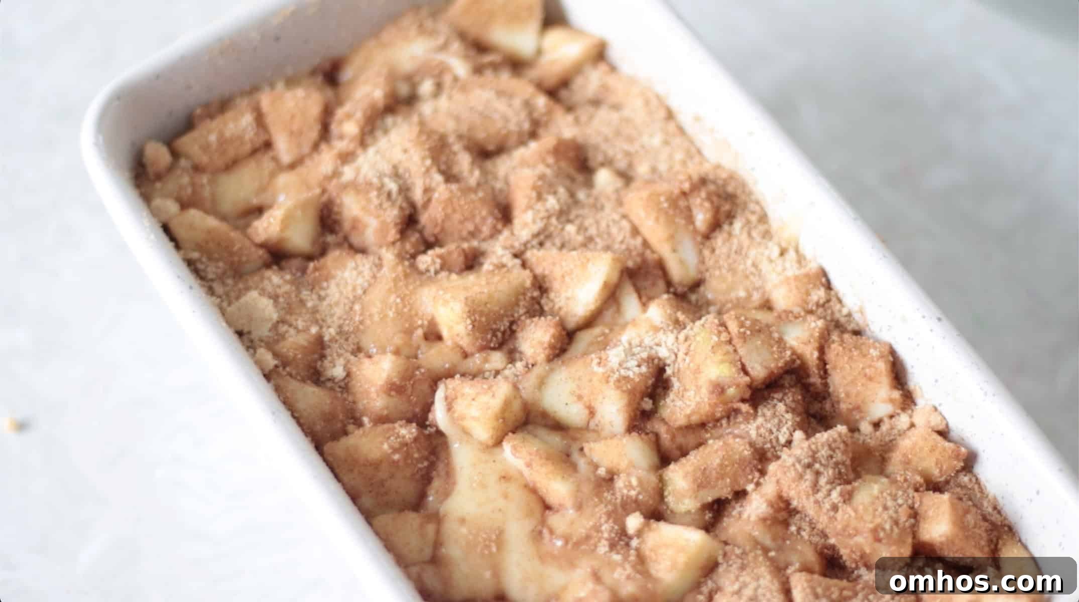 Homemade Apple Fritter Bread with Cinnamon Glaze 8 Loaf pan with apple fritter bread batter and chopped apples.