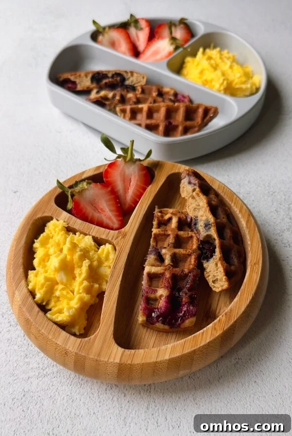 Blueberry banana waffles served with strawberries and scrambled eggs.