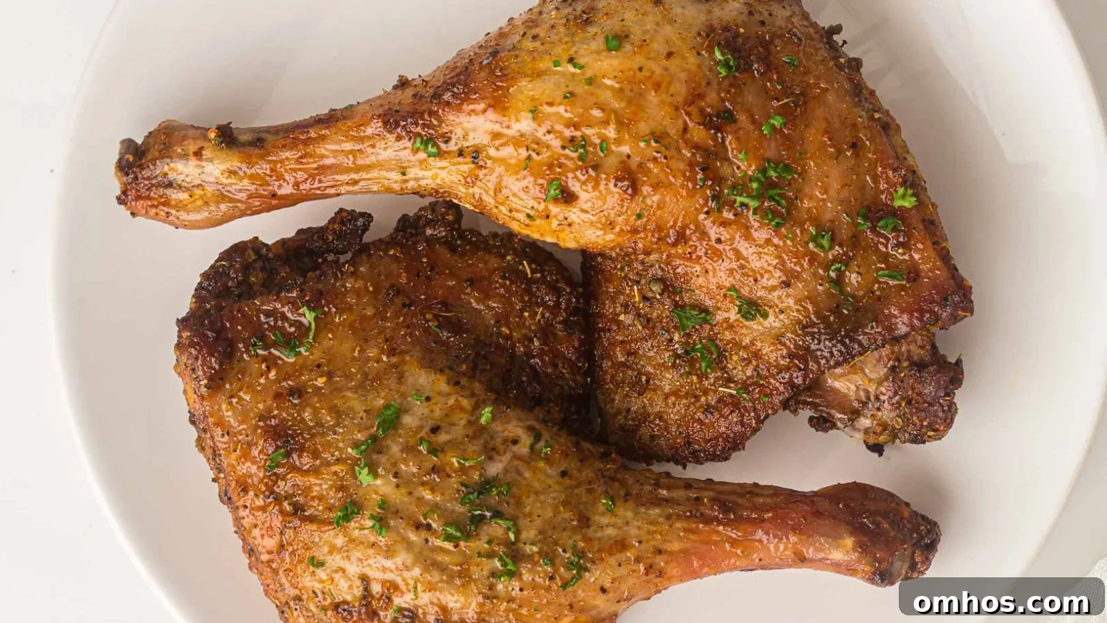 Crispy air fryer duck legs with rendered skin served with fresh herbs.