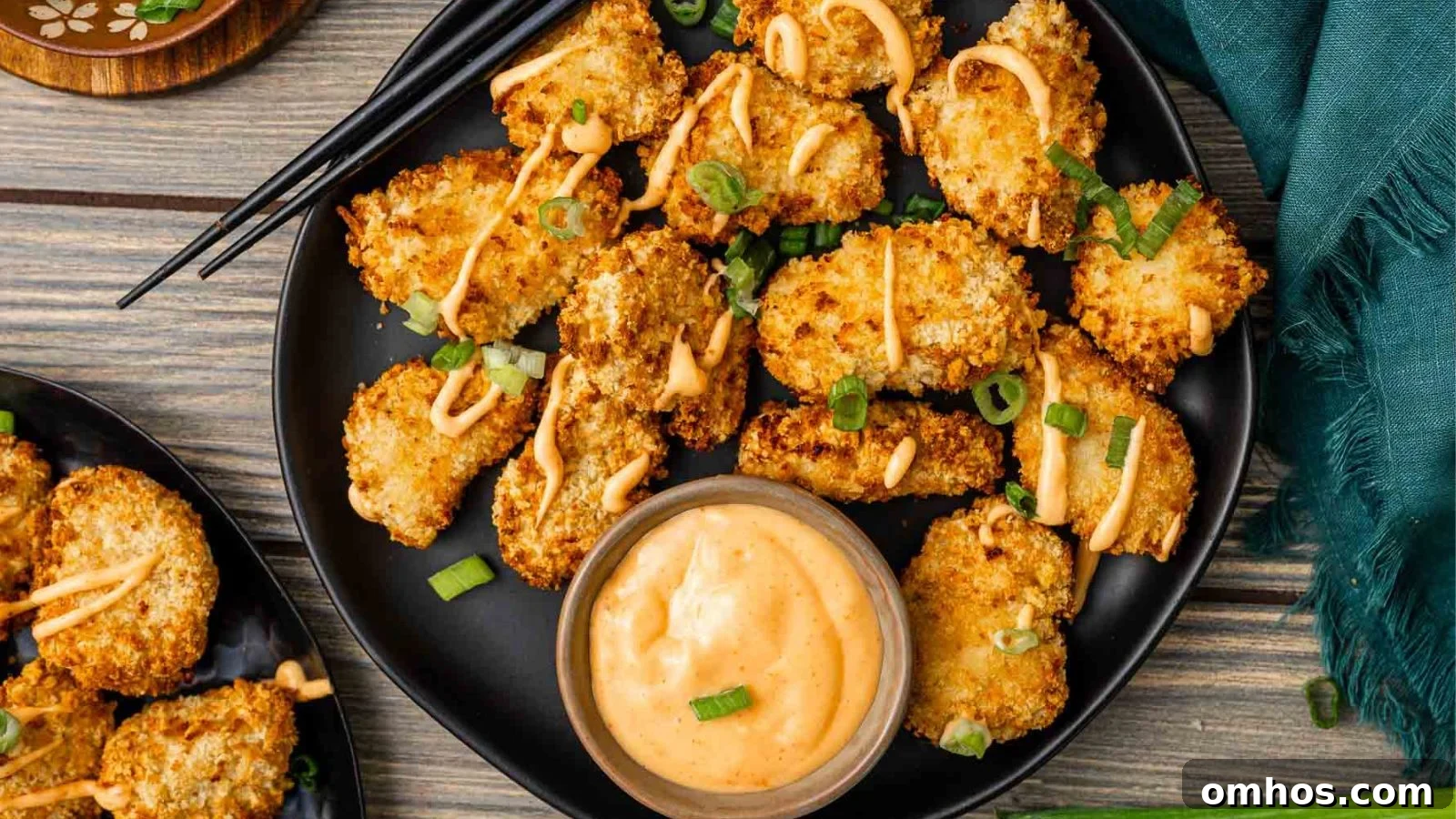 Air fryer bang bang chicken bites coated in creamy spicy sauce on a serving plate.